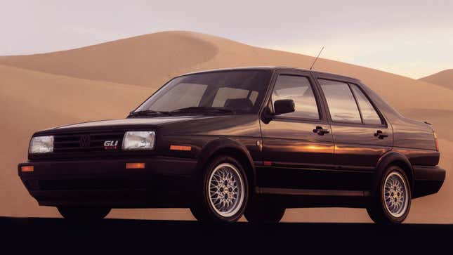 A photo of a black VW Jetta sedan parked on sand. 