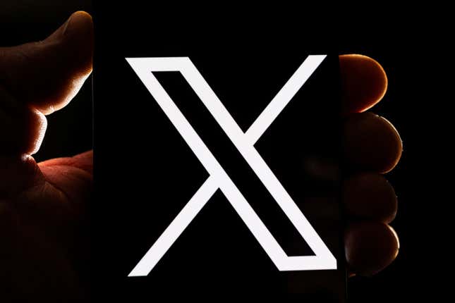 A hand holding the x logo Musk is using for Twitter