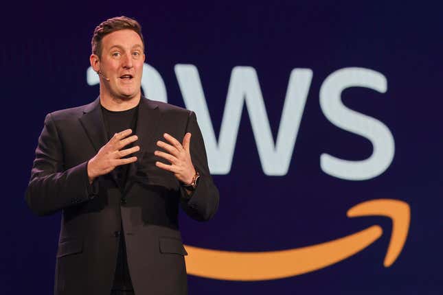 Matt Wood speaking with his hands up in front of an AWS logo