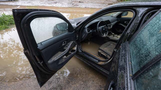 A photo of a flooded BMW's interior looking in through the driver's door. The interior is filled with muddy water