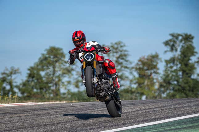 A motorcyclist does a wheelie on a racetrack on the Ducati Monster SP.