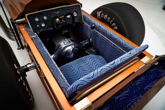 A photo of the interior of the coffin car showing the blue wavy velvet upholstery and the rear diff almost touching the seat