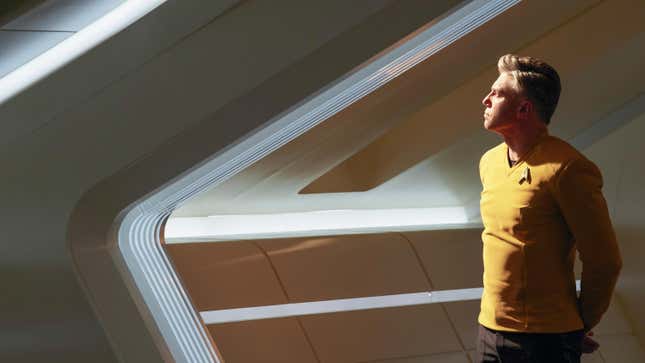 Anson Mount's Captain Christopher Pike stares out of a viewport aboard the U.S.S. Enterprise, lit up by a white-yellow light left unseen outside the ship.