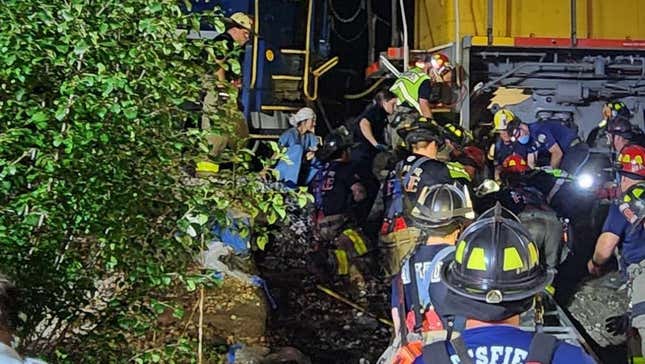 Firefighters surrounding the man tangled in the locomotive's rear axle.