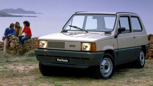 A photo of a silver Fiat Panda hatchback with people sat behind it. 