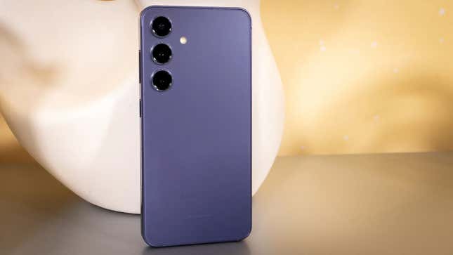 A Samsung Galaxy S24 in violet against a peach background.