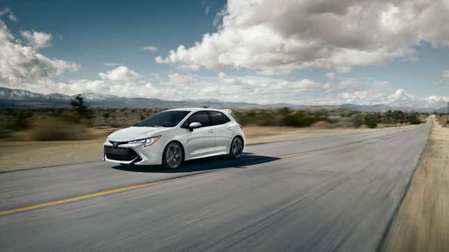 A photo of a Toyota Corolla Hatchback driving along an empty highway. 