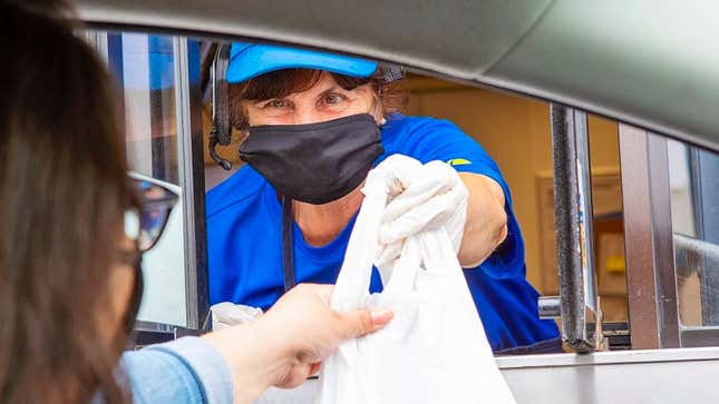 A worker hands a customer their drive-thru order. 