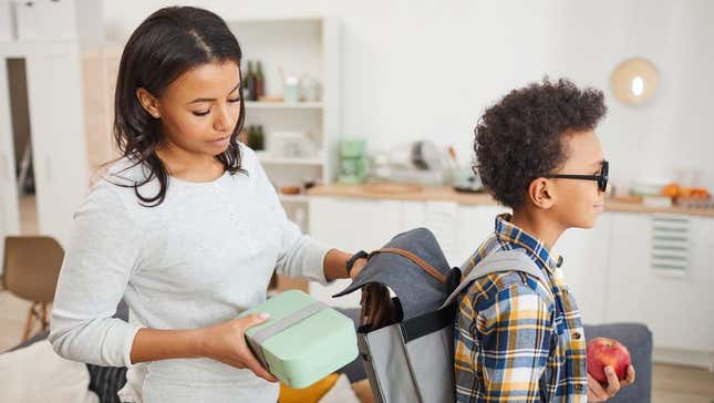 Parent putting lunch box in child's backpack