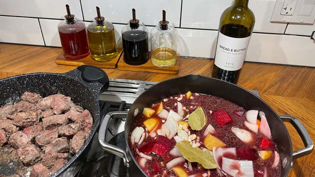Oils and vinegars in glass bottles behind a stove with stew cooking