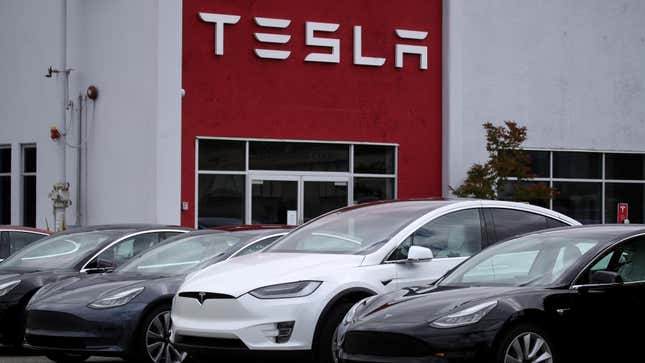 A row of Tesla cars sit outside a dealership.