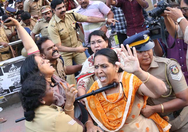 Indian policewomen detain protesting female activists in Kochi.