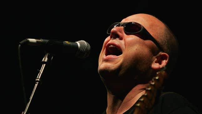 A photo of Black Francis of the Pixies singing in front of a microphone.