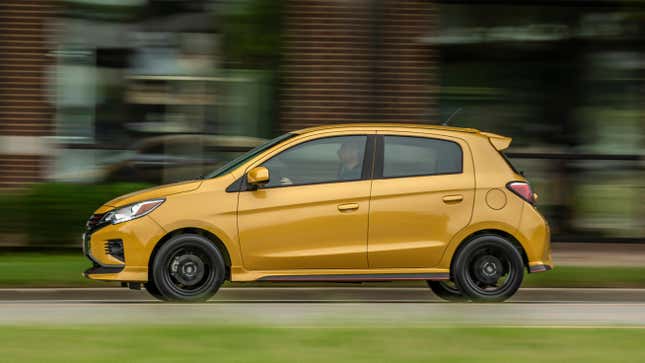 Un Mitsubishi Mirage amarillo conduciendo frente a un edificio