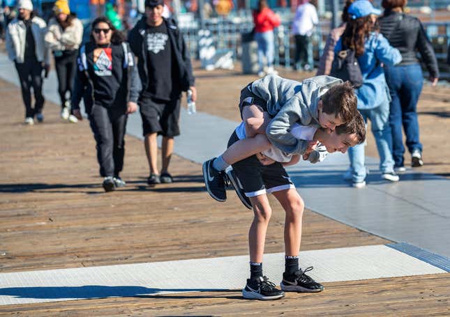 Un niño dando otro paseo a cuestas en el muelle de Santa Mónica