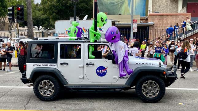 Ein weißer 4-türiger NASA-Jeep Wrangler mit aufblasbaren Aliens darauf