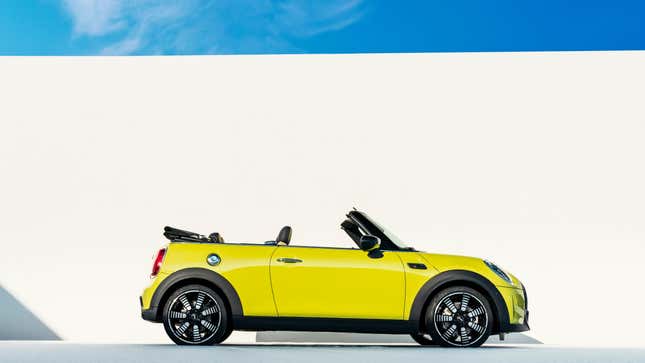 A side view of a bright yellow Mini Cooper convertible with its top down