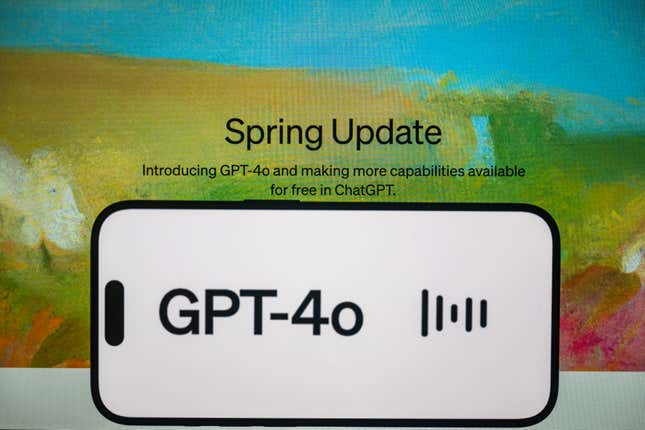 photo illustration, the 'Chat GPT-4o' logo is displayed on a mobile phone screen in front of a computer screen displaying the OpenAI's website with "Spring Update"