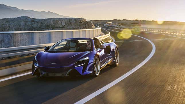 A photo of a deep blue or purple Artura Spider driving across a bridge with sun flares on the shot