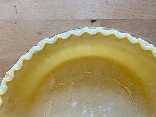 A pie crust in a glass pie dish.