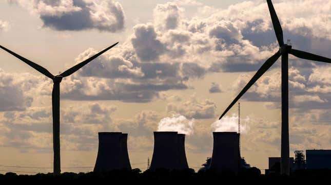 Wind turbines generate electricity as the Drax Power Station in the background also generates electricity on June 29, 2023 in Selby, England. 