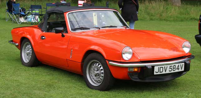 A red 1980 Spitfire parked on a green lawn