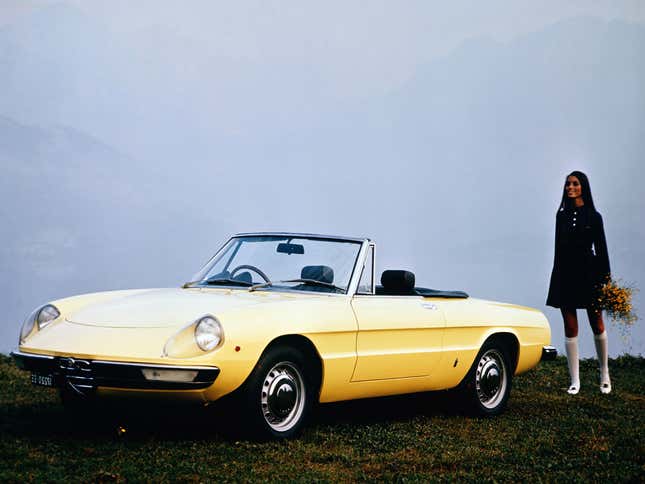 A bright yellow Alfa Spider in front of a foggy background