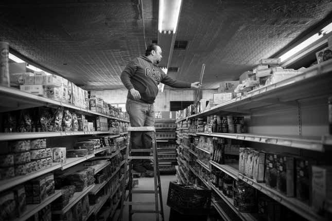 Abdullah Ferdous, who works as an electrician, changes a lighting fixture at a food market in Brooklyn.