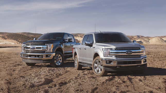 Two Ford F-150 pickup trucks parked on dirt.