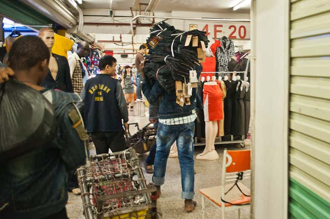 A trader carries a shipment of jeans through a mall in Guangzhou. Many traders stay in Guangzhou after their visas expire, hoping to remain undetected until they make enough money to go home. Some are caught in regular police stings, and others give up, relying on the charity of African-community organizations for airfare home.
