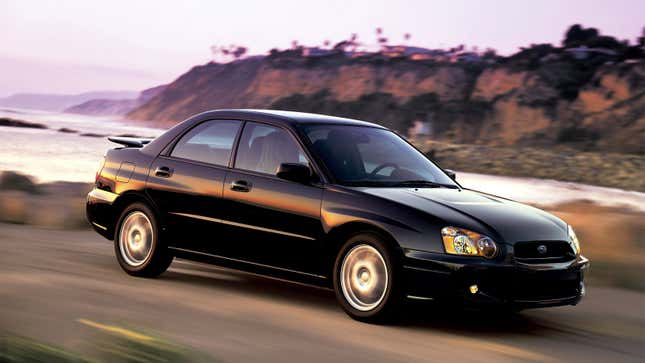 A photo of a black Subaru Impreza driving on a highway. 