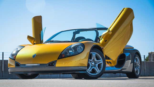 A front three quarters shot of the bright yellow Renault Sport Spider parked wiht its butterfly doors up