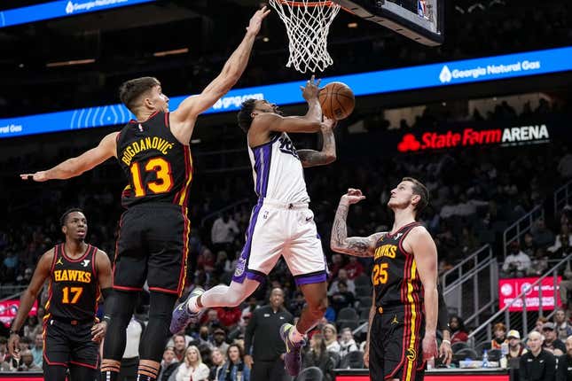 Dec 29, 2023; Atlanta, Georgia, USA; Sacramento Kings guard Malik Monk (0) tries to score past Atlanta Hawks guard Bogdan Bogdanovic (13) during the first half at State Farm Arena.