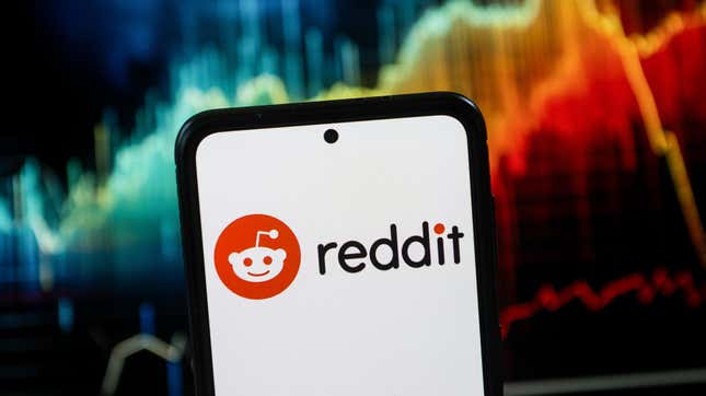 A phone bearing the Reddit logo sits in front a rainbow-colored series of line graphs.