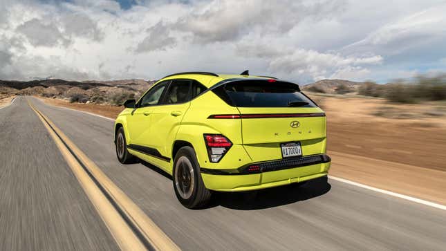 A rear 3/4 shot of a highlighter yellow Kona Electric driving in the desert 