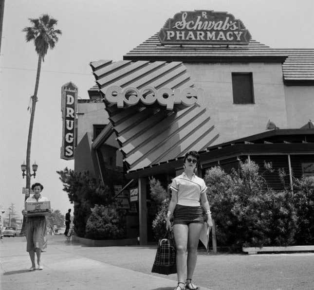 may 1954 a woman walks outside Googies Coffee Shop and Schwab's Pharmacy in Los Angeles, CA.