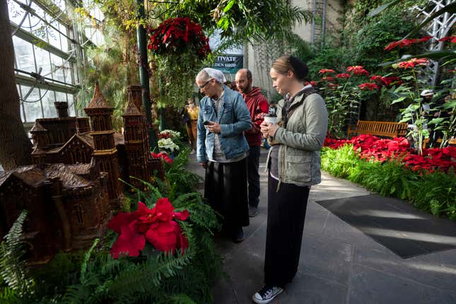 Lora Wade and her husband Jerry Wadel, back center, and her sister Valley Mobley, right, all members of the Mennonite Church, look at the display of different varieties of poinsettias at the Smithsonian&#39;s U.S. Botanical Garden, Saturday, Dec. 16, 2023, in Washington. (AP Photo/Manuel Balce Ceneta)