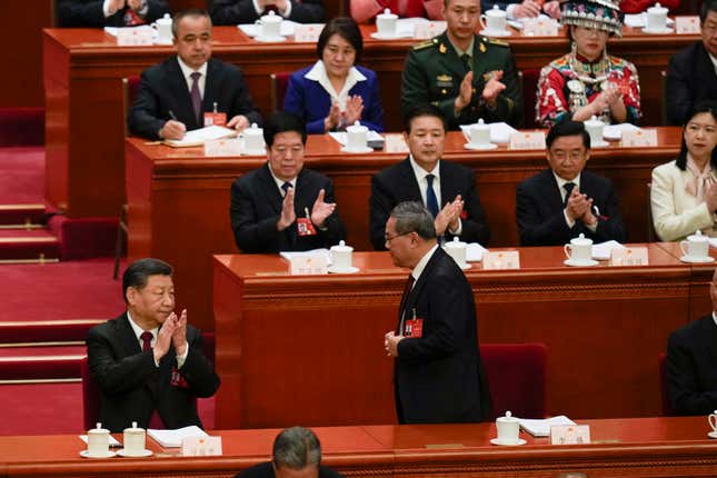 Chinese President Xi Jinping, left, applauds as Chinese Premier Li Qiang, center, prepares to give the opening speech during the opening session of the National People&#39;s Congress (NPC) at the Great Hall of the People in Beijing, China, Tuesday, March 5, 2024. (AP Photo/Ng Han Guan)