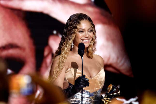 Beyonce holding a reward and the mic stand in her other hand, smiling