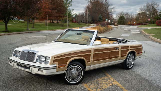 Vue de trois quarts avant d’une décapotable Chrysler LeBaron de 1985 en blanc avec boiseries