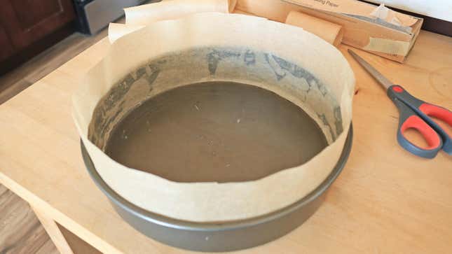 A cake pan with parchment paper lining the walls. 