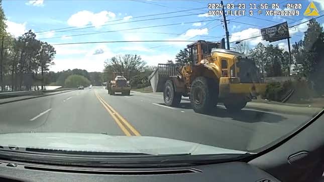 A photo of two front-loaders chasing down a highway. 