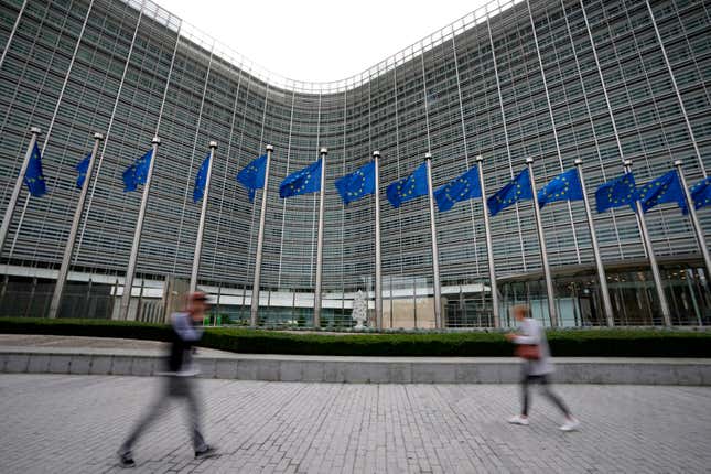 FILE - European Union flags wave in the wind as pedestrians walk by EU headquarters in Brussels, on Sept. 20, 2023. Three of the world&#39;s biggest porn websites face new requirements in the European Union including verifying the ages of users, the bloc said Wednesday, Dec. 20, 2023, as it expanded the reach of its digital law designed to keep people safe on the internet. (AP Photo/Virginia Mayo, File)