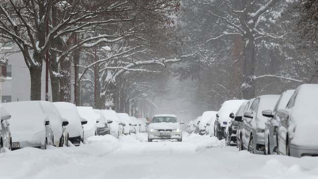 A car drives down a snow-covered road 