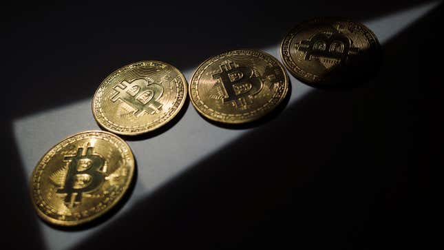 A sliver of light shining on four physical bitcoin representations.