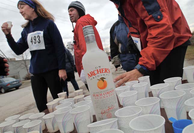 Personas tomando pequeños vasos desechables de aguardiente de melocotón