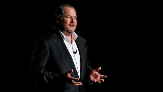 Salesforce CEO Marc Benioff speaks on a darkened stage with his hands outstretched