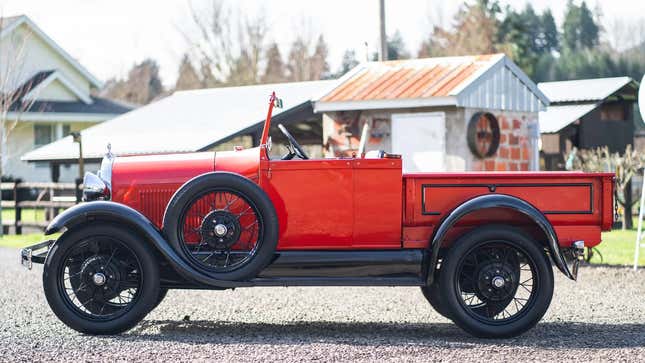 La vista lateral de una camioneta Ford Modelo A Roadster roja del 29 con la capota bajada