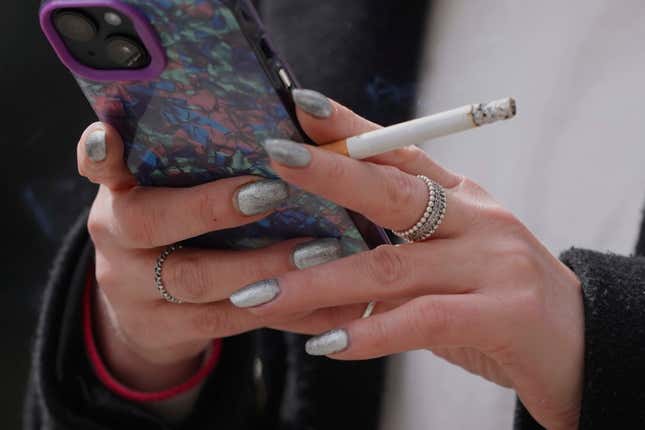 A woman smokes on a street, in London, Tuesday, April 16, 2024. A bold plan to ban anyone born after 2008 from ever legally buying cigarettes in Britain faces its first test in Parliament. The bold plan has divided the governing Conservatives, with some hailing its public health benefits and others condemning it as state overreach. (AP Photo/Kin Cheung)