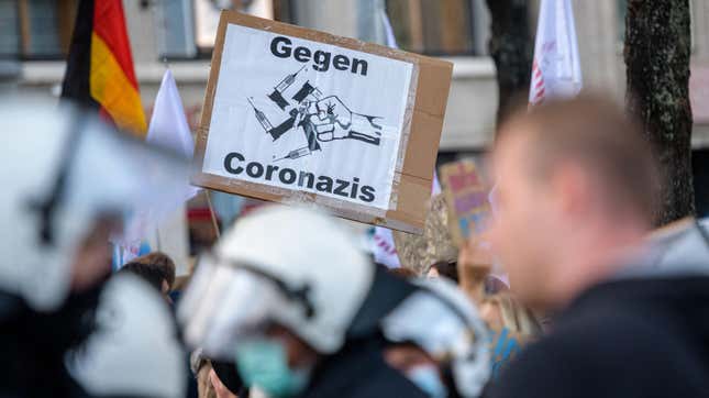 An anti-lockdown protester holds up a poster reading “Against Coronazis” during a demonstration of Germany’s “Querdenker” (Lateral Thinkers) movement on November 6, 2021 in Leipzig, eastern Germany. 